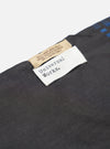 An angled view of the Universal Works Black/Blue Jacquard Silk Scarf folded to show its soft drape and double-sided woven finish. The blue and black silk accessory is displayed clearly against a clean white backdrop.