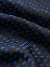 A close-up swatch detail of the Universal Works Black/Blue Jacquard Silk Scarf. The extreme close-up view emphasizes the intricate weave of the black and blue silk jacquard fabric and its fine thread structure against a plain background.