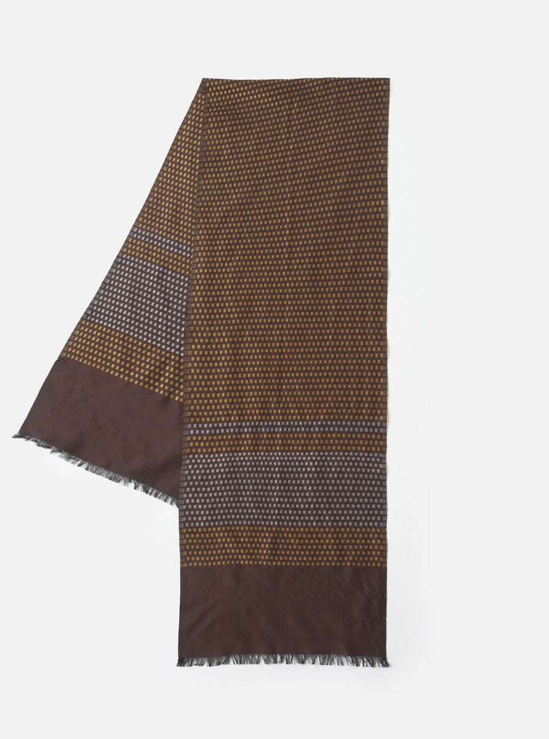 A full view of the Universal Works Brown/Sky/Gold Jacquard Silk Scarf laid flat against a neutral backdrop. The silk scarf shows off a decorative pattern in brown, sky blue, and gold woven directly into the fabric.