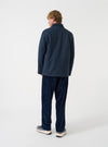 A model wearing the Blue/Black Harris Tweed OG Bakers Chore Jacket, viewed from behind against a plain background. The image displays the relaxed fit, straight hem, and back panel of the dark tweed jacket.