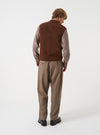 A model wearing the Brown Wool Herringbone Pleated Track Pant, shown from behind against a plain background. The image focuses on the rear waistband, relaxed fit through the thighs, and tapered hem.