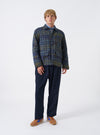 A back view of a model wearing the Olive Shadows Check Franck Jacket. The photo emphasizes the rear pattern alignment of the olive green check cotton fabric, structured shoulders, and relaxed cut set against a plain neutral backdrop.