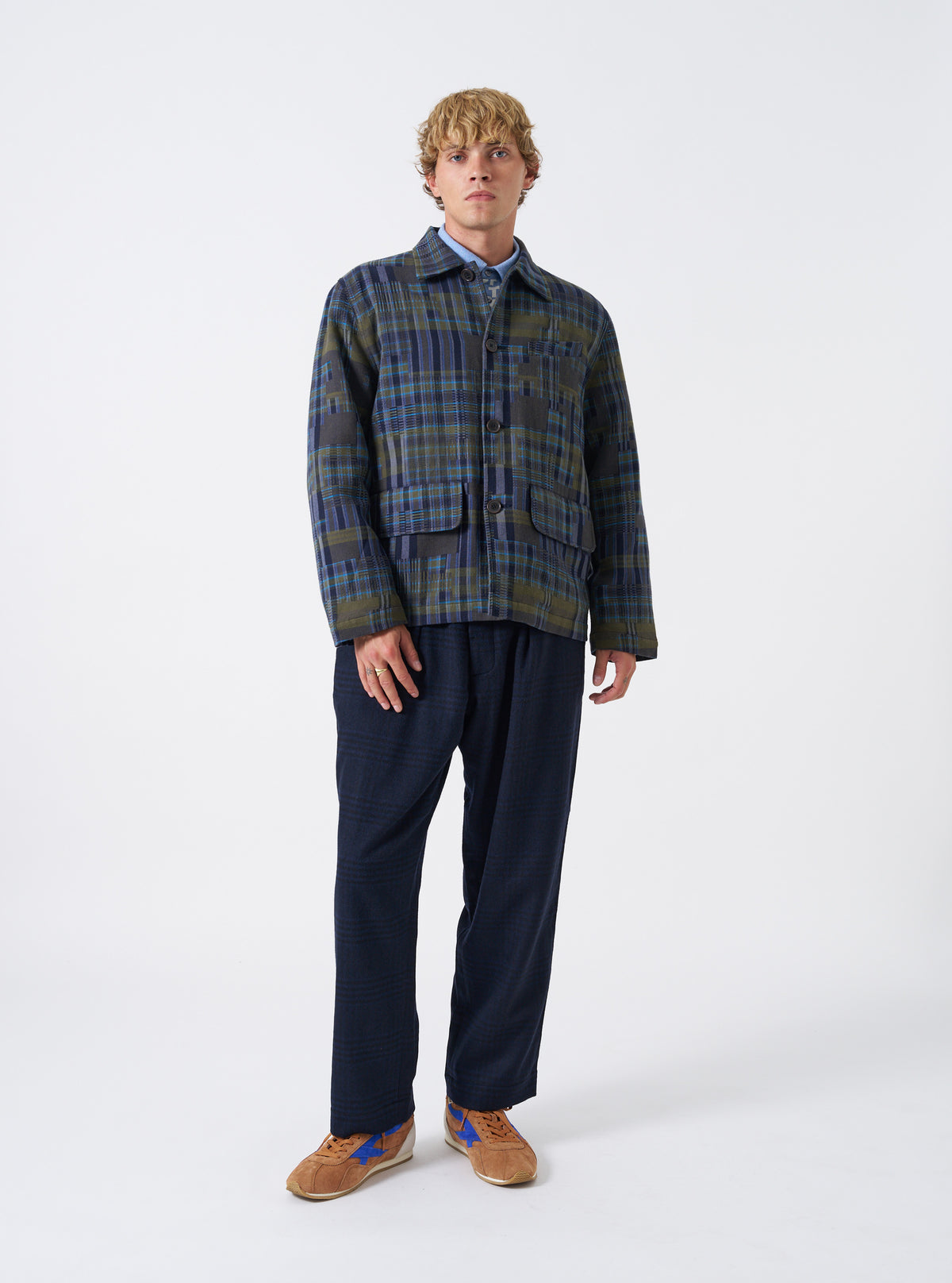 A back view of a model wearing the Olive Shadows Check Franck Jacket. The photo emphasizes the rear pattern alignment of the olive green check cotton fabric, structured shoulders, and relaxed cut set against a plain neutral backdrop.
