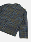 Close-up flat lay of the Franck Jacket in olive shadows check on a white studio backdrop. The shot shows the back panel and right sleeve, highlighting the textured woven check fabric in olive, navy, grey and blue. A narrow shirt collar and plain cuff are visible.