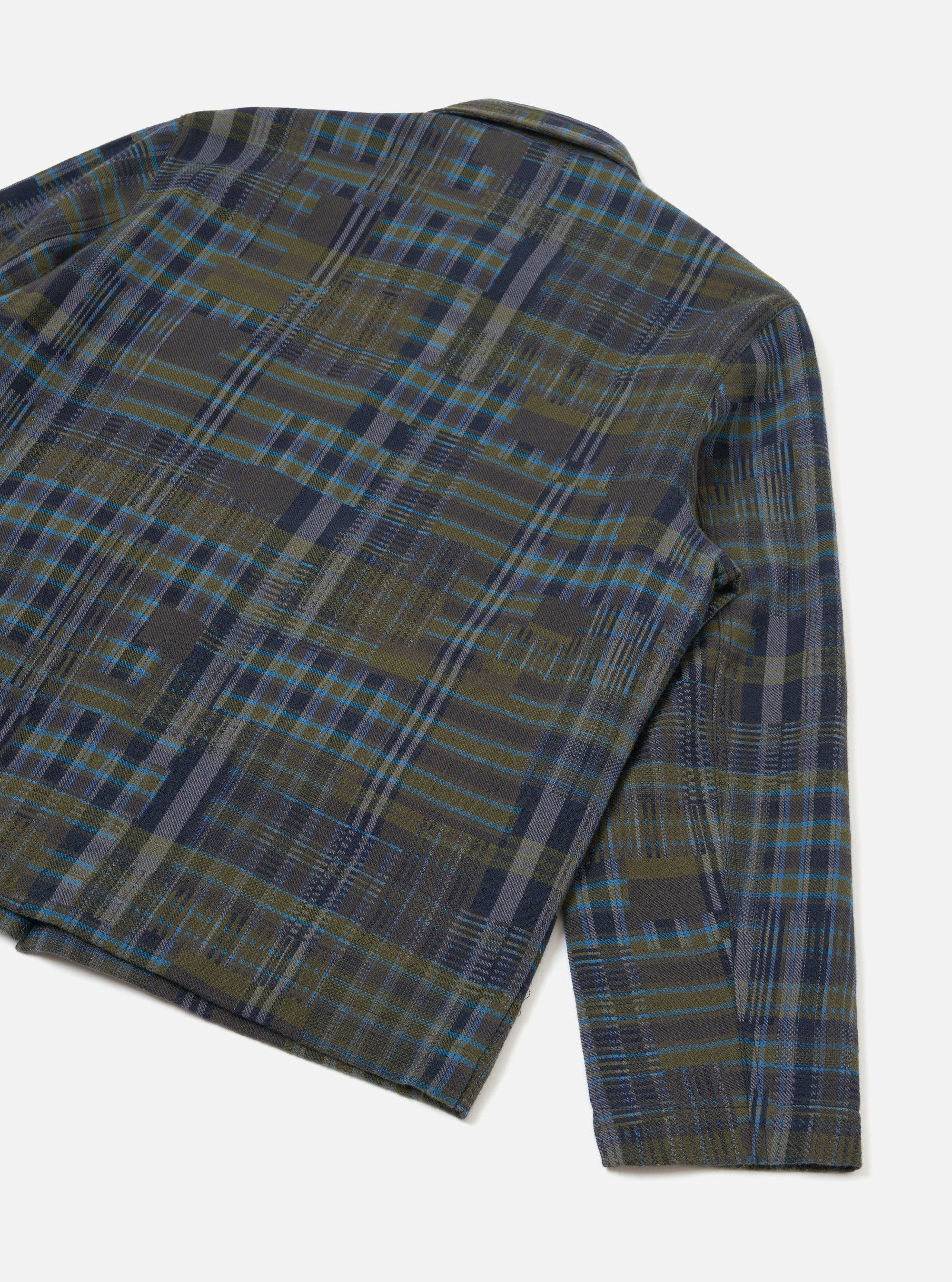 Close-up flat lay of the Franck Jacket in olive shadows check on a white studio backdrop. The shot shows the back panel and right sleeve, highlighting the textured woven check fabric in olive, navy, grey and blue. A narrow shirt collar and plain cuff are visible.