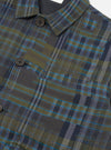 Close-up of the olive shadows check Franck jacket laid flat, showing the point collar, dark navy lining visible at the neckline, and a button-front placket with dark four-hole buttons. A chest patch pocket with a button tab is visible. The woven fabric shows a bold check in olive, navy and teal on a white studio background.