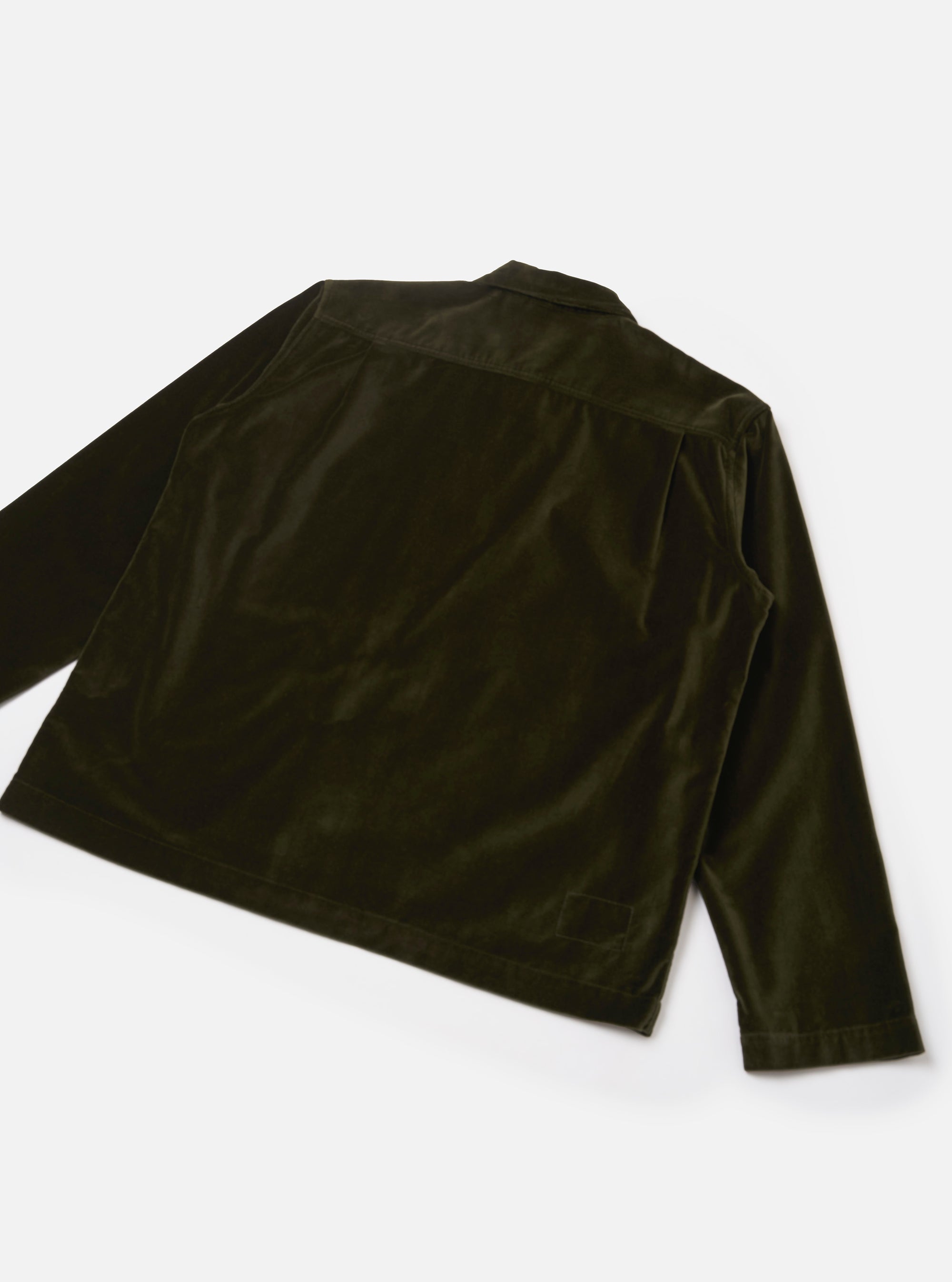 Back view of an olive velvet zip shirt, laid flat on a light grey surface. The smooth, lustrous velvet fabric shows light-catching sheen across the back panel and long sleeves. A rear yoke seam runs across the upper back, and a small welt pocket sits at the lower right. The cuffs are plain with no visible buttons.