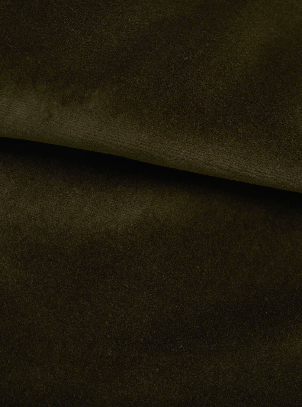 Close-up of olive green velvet fabric, folded to show its dense, soft pile and smooth surface. The deep khaki-olive tone has a subtle lustre, with a diagonal fold creating a sharp ridge across the frame. No garment details are visible.