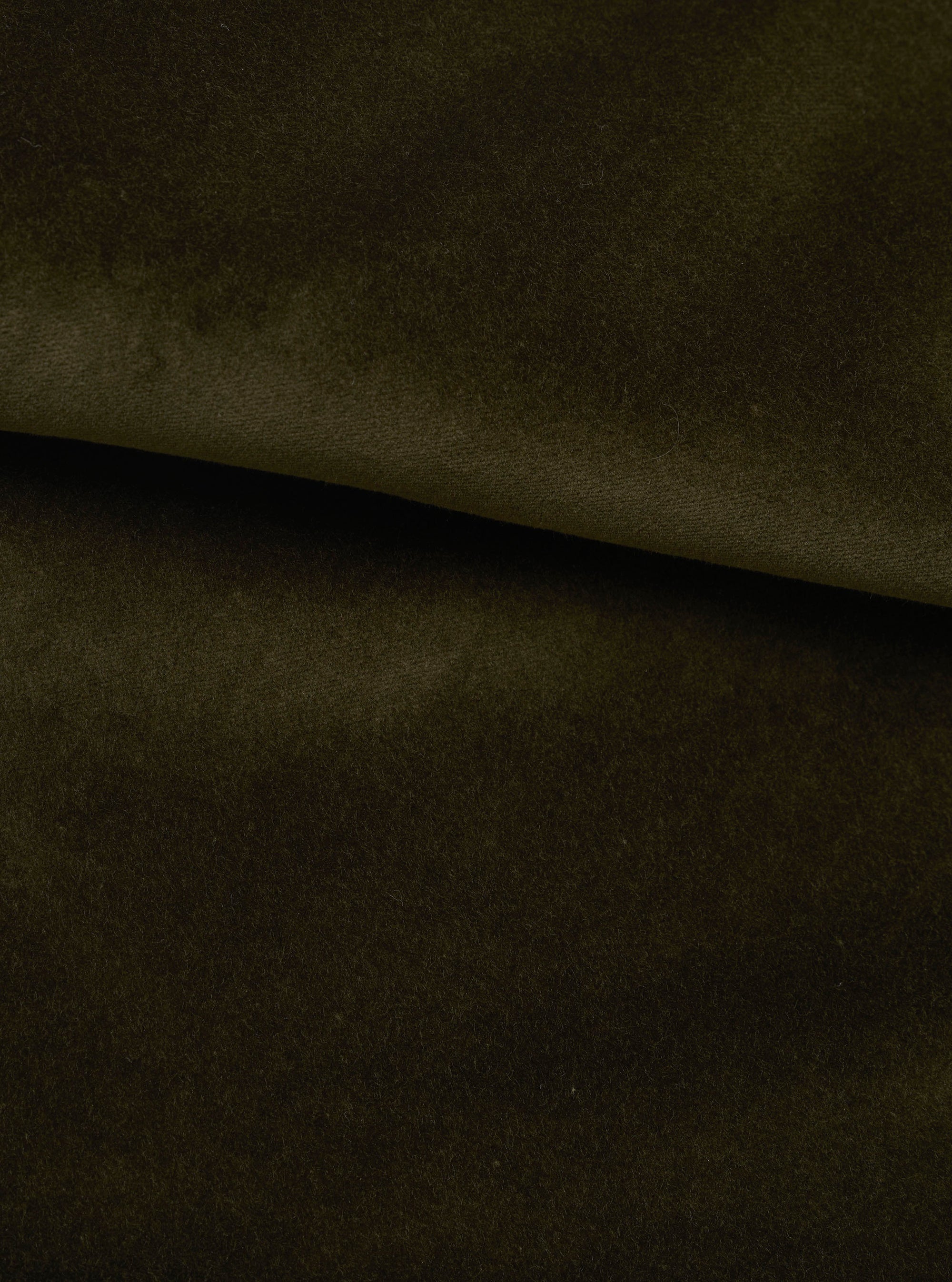 Close-up of olive green velvet fabric, folded to show its dense, soft pile and smooth surface. The deep khaki-olive tone has a subtle lustre, with a diagonal fold creating a sharp ridge across the frame. No garment details are visible.