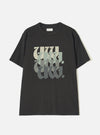 Black single jersey t-shirt laid flat on a white studio surface. Crew neck with a small Universal Works woven label at the back neck. Short sleeves with a relaxed fit. Large chest graphic featuring stacked "UW" lettering in a blackletter style, fading from cream through sage green to dark grey.