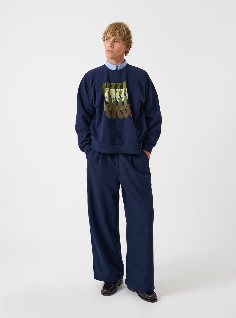 A front product view of the Universal Works Navy Brush Back Sweat UW UW Print Raglan Sweatshirt on a plain background. The navy blue cotton pullover features long raglan sleeves, a ribbed crew neck, ribbed hem, and front chest detail.