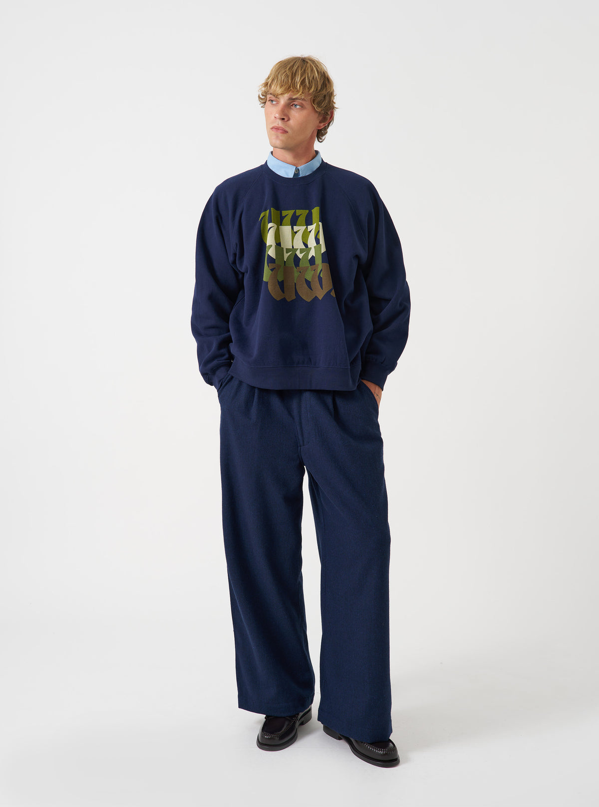 A front product view of the Universal Works Navy Brush Back Sweat UW UW Print Raglan Sweatshirt on a plain background. The navy blue cotton pullover features long raglan sleeves, a ribbed crew neck, ribbed hem, and front chest detail.