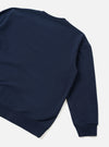 A back view product shot of the Universal Works Navy Brushback Sweat Cool Of Jazz Loose Sweatshirt set against a plain background. The image displays the relaxed cut, smooth rear navy cotton fabric, and ribbed hemline of the garment.