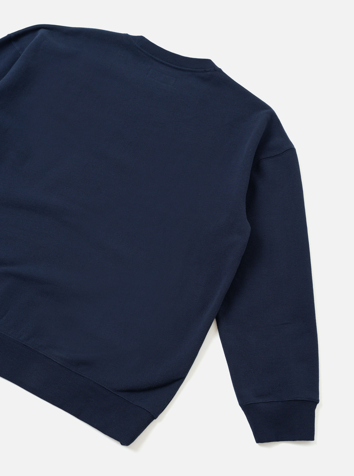 A back view product shot of the Universal Works Navy Brushback Sweat Cool Of Jazz Loose Sweatshirt set against a plain background. The image displays the relaxed cut, smooth rear navy cotton fabric, and ribbed hemline of the garment.