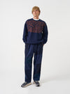 A model wearing the Universal Works Navy Brushback Sweat Cool Of Jazz Loose Sweatshirt, shown from the front. The navy blue sweatshirt features a loose casual cut, crew neck, and chest graphic print against a plain background.