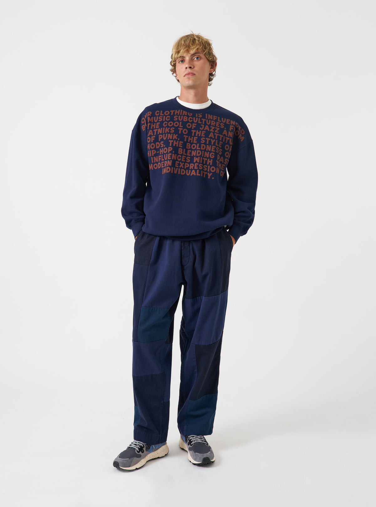 A model wearing the Universal Works Navy Brushback Sweat Cool Of Jazz Loose Sweatshirt, shown from the front. The navy blue sweatshirt features a loose casual cut, crew neck, and chest graphic print against a plain background.