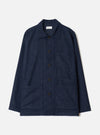 Navy check wool mix bakers overshirt in a fine grid check pattern on a plain light grey studio backdrop. Flat lay. Camp collar, five dark horn-effect buttons down the centre front, one chest patch pocket and two large lower patch pockets. Long sleeves with plain cuffs. Universal Works woven label visible at the neck.