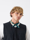 A selection of folded neckerchiefs including the Forest Green Jazz/Beatniks Print Neckerchief, displayed against a neutral studio backdrop highlighting its graphic text pattern.