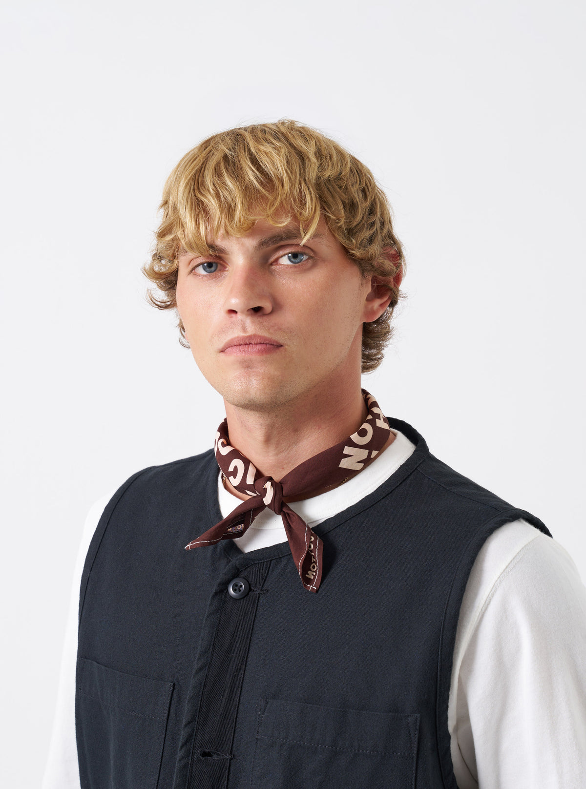 A group composition of accessories featuring the Brown Jazz/Beatniks Print Neckerchief against a plain backdrop, highlighting the rich brown color and bold jazz-themed text graphic.