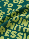 A close-up fabric swatch image of the Forest Green Jazz/Beatniks Print Neckerchief against a plain neutral background, showing the intricate jazz-inspired graphic text design and cotton weave.
