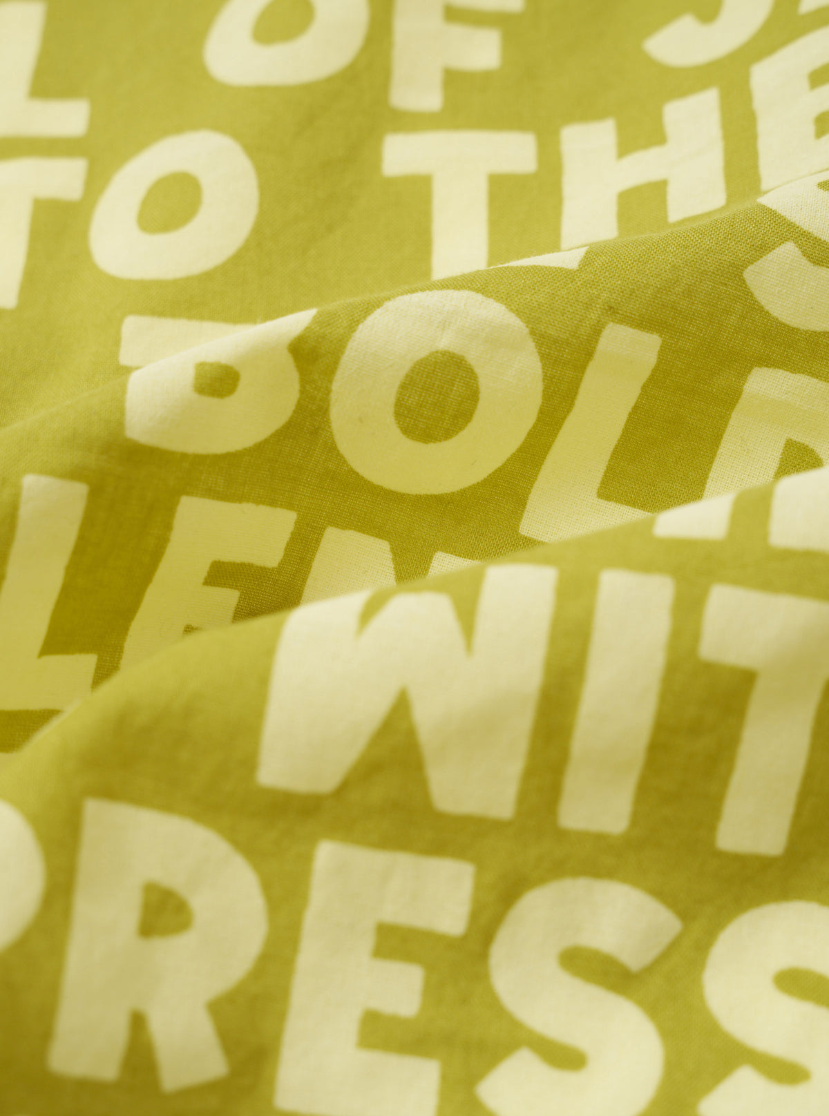 A close-up fabric swatch view of the Light Olive Jazz/Beatniks Print Neckerchief on a solid backdrop, detailing the light olive tone, jazz graphic print, and fine cotton fabric texture.