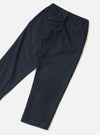 Navy wool-mix oxford trousers laid flat on a light grey seamless surface. The fabric features a subtle glen check pattern in navy and dark green. The elasticated waistband is visible at the top, with a buttoned flap pocket on the left hip and a small button-fastened welt pocket on the right rear. Tapered leg with a plain hem.