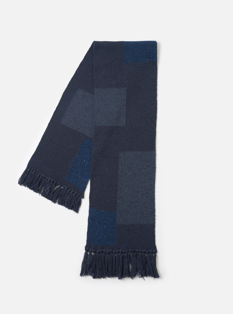 The Navy British Wool Scarf laid out flat against a clean, neutral studio background. Crafted from warm navy British wool, the rectangular scarf features ribbed ends and a clean, minimalist design.