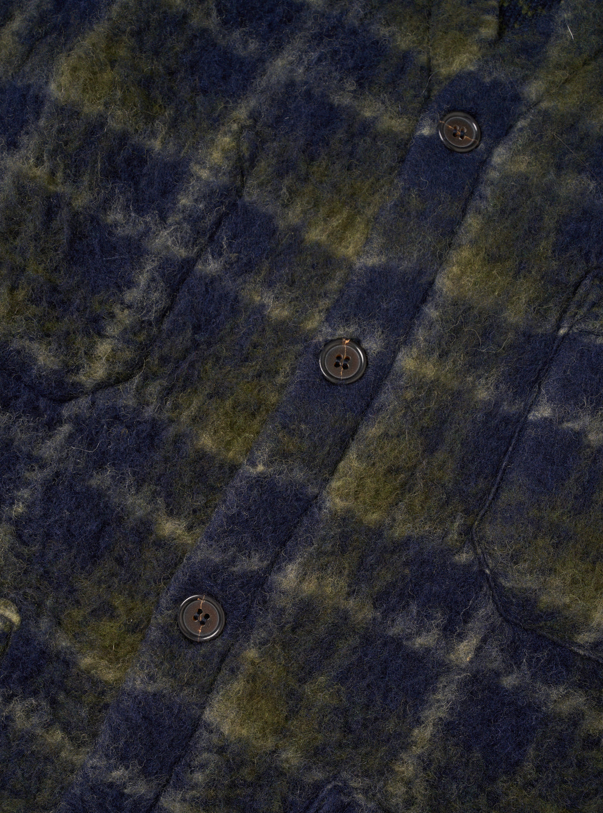 A detail image of the Navy/Olive Check Daffy Fleece Mix Cardigan on a plain background, highlighting the front V-neckline, button placket, patch pockets, and soft textured check fleece material.