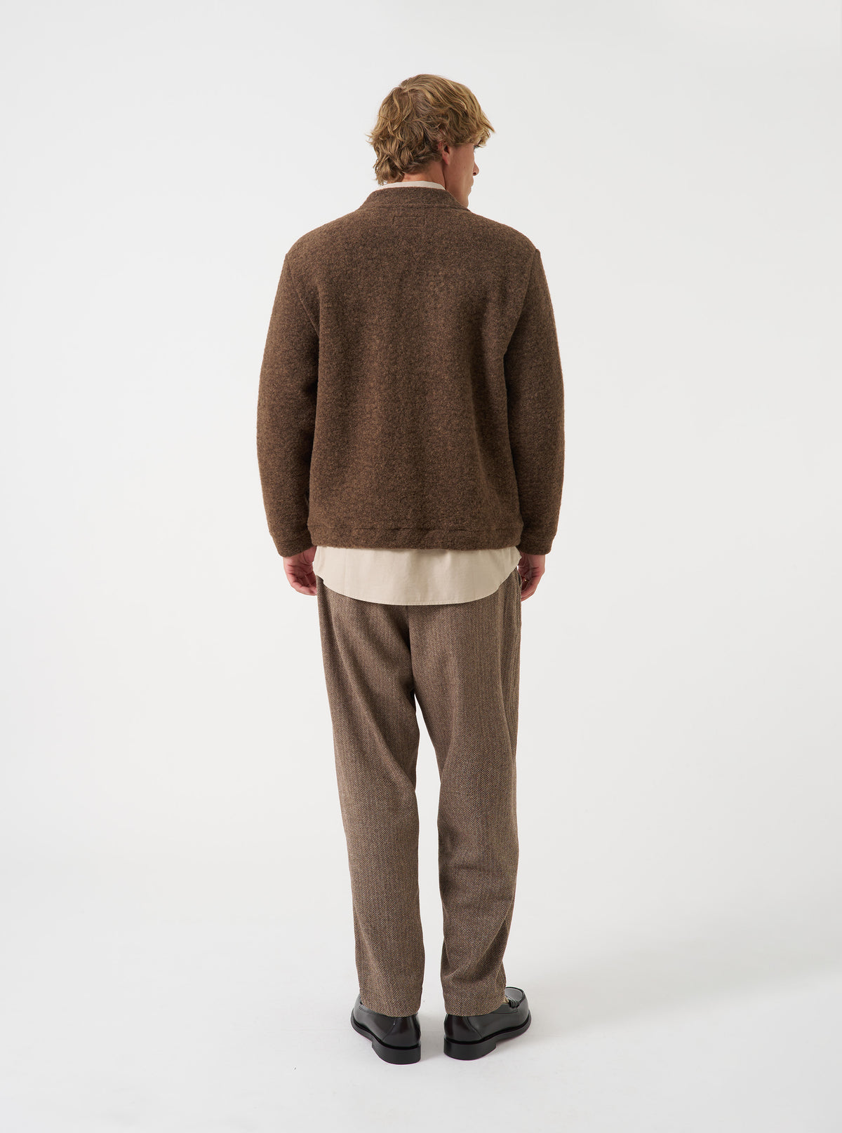 A model wearing the Brown Marl Wool Fleece Advance Cardigan against a plain studio background, shown from an alternate angle to highlight the loose fit, comfortable drape, and soft wool fleece finish.
