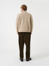 A model wearing the Fawn Wool Fleece Advance Cardigan captured from an alternate angle against a plain studio background, highlighting the casual fit, soft drape, and neutral fawn wool fleece texture.