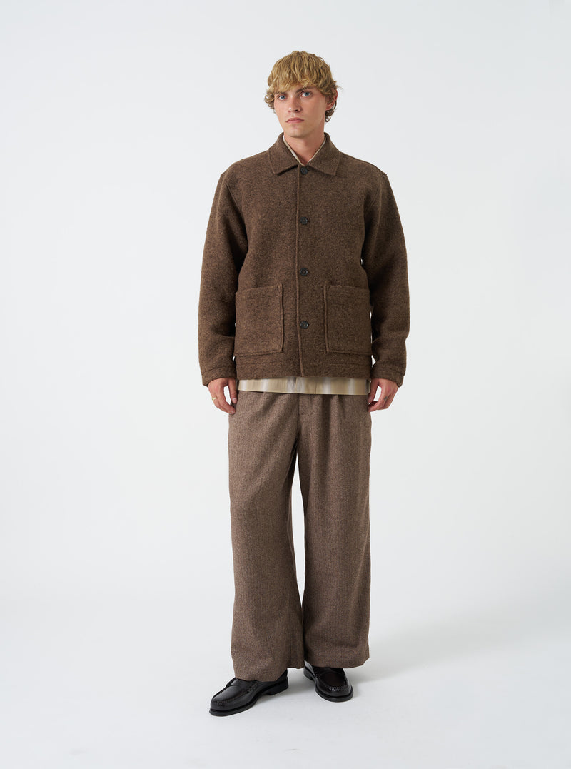 A male model wears the Brown Marl Wool Fleece Rams Jacket against a plain studio background. The jacket is styled unbuttoned over a shirt, highlighting its boxy fit, classic collar, and spacious patch pockets.