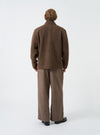 A male model is shown from the side wearing the Brown Marl Wool Fleece Rams Jacket in a studio setting. The shot demonstrates the relaxed silhouette, drop shoulder detail, and comfortable fit of the garment.