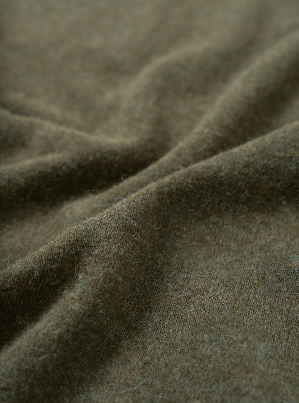 Close-up fabric swatch of the Olive Recycled Wool Mix SJ Pullover L/S Shirt, displaying the olive green heathered finish and fine weave of the recycled wool and polyester blend single jersey.