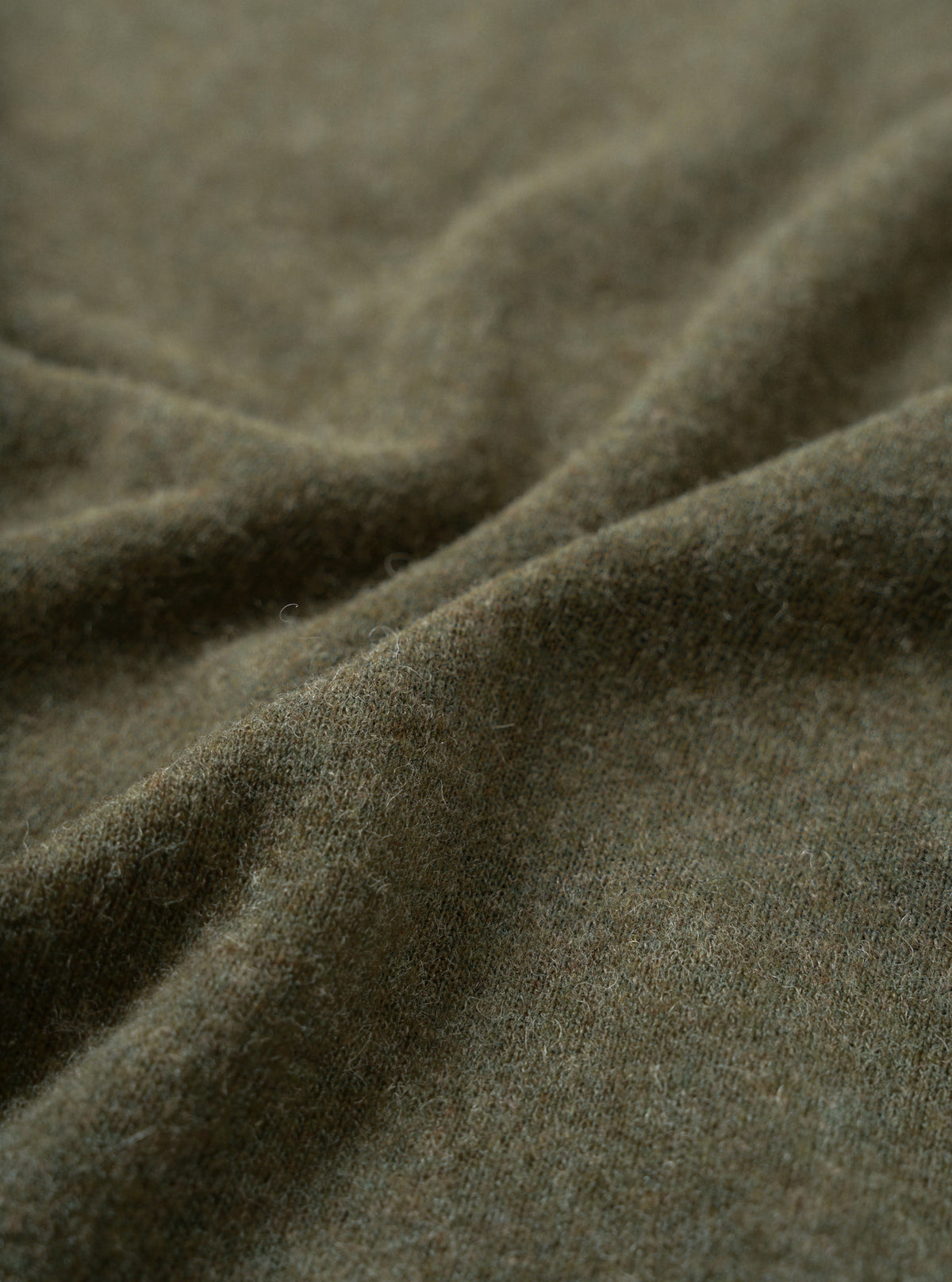 Close-up fabric swatch of the Olive Recycled Wool Mix SJ Pullover L/S Shirt, displaying the olive green heathered finish and fine weave of the recycled wool and polyester blend single jersey.