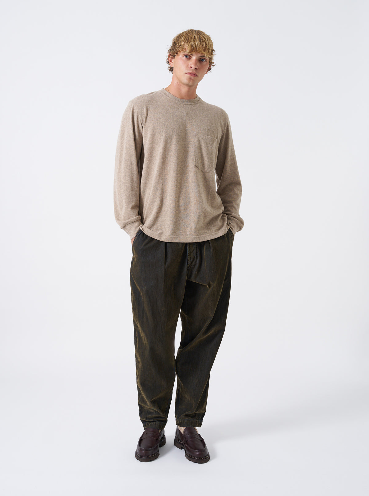 A model wearing the Dark Sand Recycled Wool Mix SJ L/S Pocket Tee against a neutral studio backdrop. The long-sleeve shirt features a relaxed fit, classic crew collar, and a single chest patch pocket.