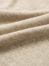 Close-up of dark sand recycled wool mix fabric, showing a fine knit texture with a soft, slightly haired surface. The oatmeal-toned yarn has subtle flecks of grey and brown throughout. Gentle folds run diagonally across the frame, highlighting the fabric's drape and weight.