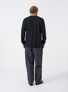 Alternate view of a model wearing the Black Recycled Wool Mix SJ L/S Pocket Tee in a studio setting. The long-sleeve tee showcases a comfortable fit, ribbed crew collar, and front chest patch pocket.