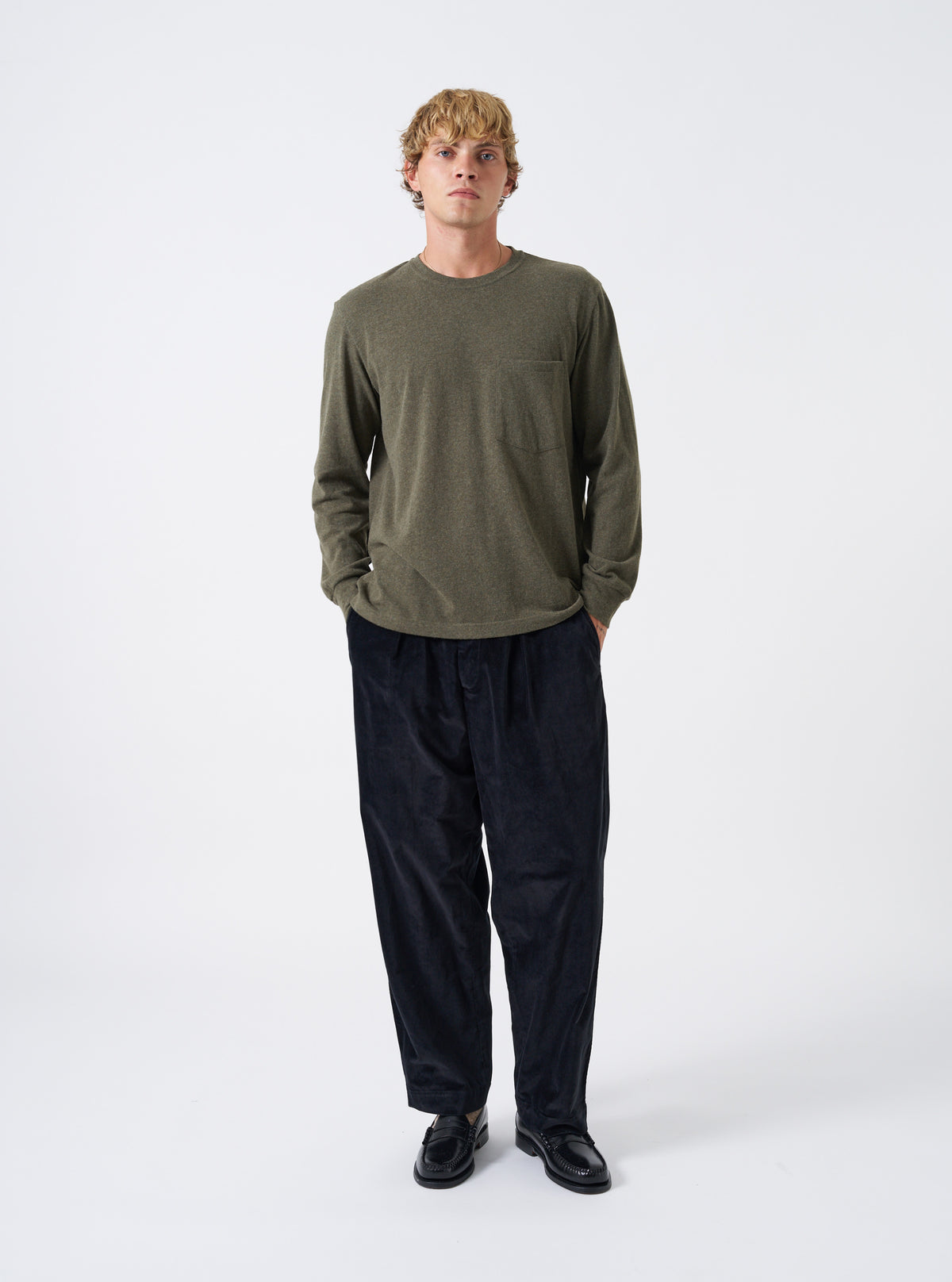 A model wearing the Olive Recycled Wool Mix SJ L/S Pocket Tee against a plain backdrop. The olive marl long-sleeve shirt features a comfortable crewneck, front chest pocket, and loose fit.