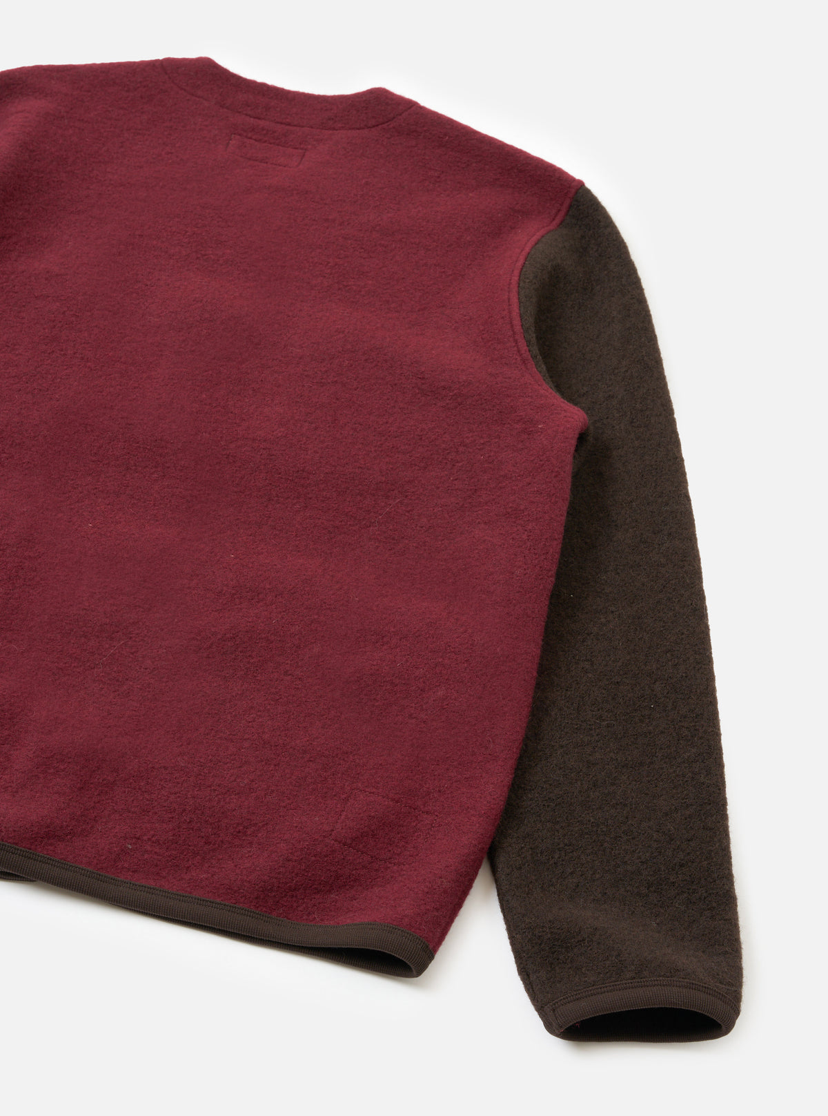 A male model seen from behind wearing the Berry/Brown Wool Fleece Cardigan against a plain white studio background, displaying the relaxed fit, clean back panel construction, and rib-bound hem in a rich brown tone.