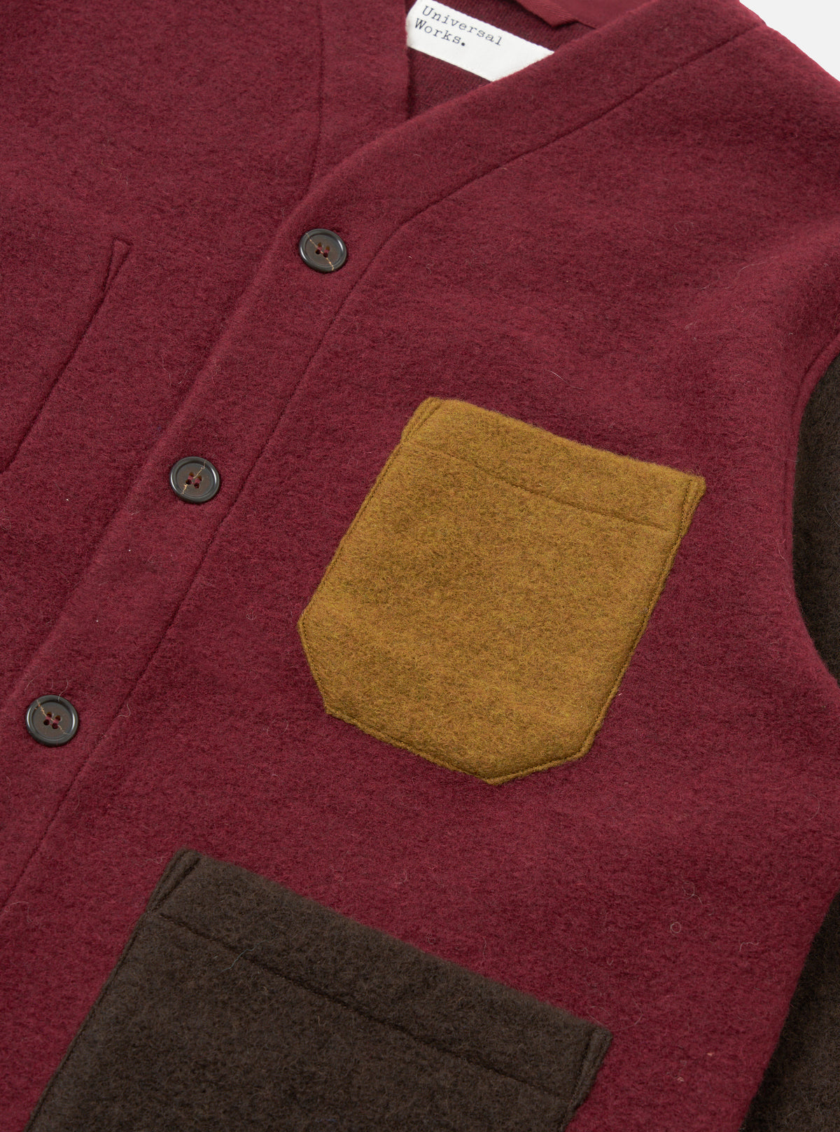 A close-up detailed shot of a model wearing the Berry/Brown Wool Fleece Cardigan on a plain backdrop, highlighting the five-button front placket, single patch chest pocket, and two-tone wool fleece texture.