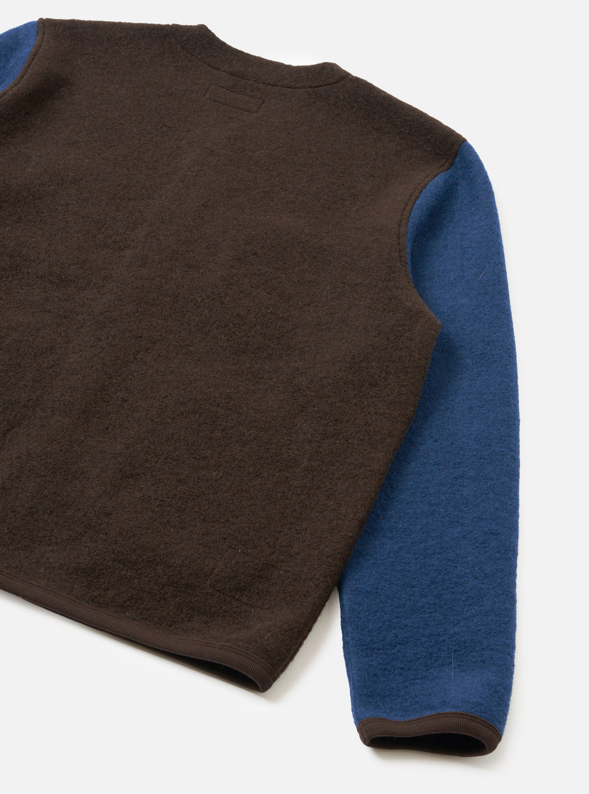A back view of a male model wearing the Brown/Indigo Wool Fleece Cardigan against a clean light background, highlighting the comfortable regular fit, shoulder seams, and dark indigo wool fleece back panel.