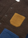 A detailed close-up shot of a model wearing the Brown/Indigo Wool Fleece Cardigan against a plain backdrop, showing the front button details, neat edge binding, patch pocket, and heathered brown-indigo material.