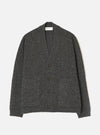 A male model wearing the Black Wool Fleck Langdale Cardigan set against a plain light background. The front view showcases the buttoned front closure, patch pockets, V-neckline, and specked wool fleck pattern.