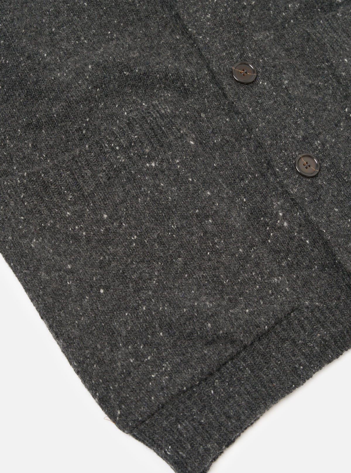 A close-up image of a model wearing the Black Wool Fleck Langdale Cardigan on a neutral background, highlighting the button placket, V-neck styling, textured knit finish, and flecked yarn details.