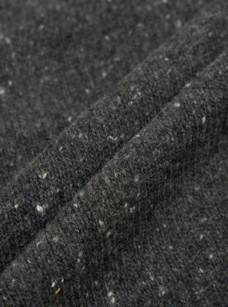 A fabric swatch close-up image of the Black Wool Fleck Langdale Cardigan on a plain light background, highlighting the rich black wool blend base adorned with characteristic subtle multi-colored flecks.
