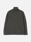 A model wearing the Black Wool Fleck Roll Neck against a neutral studio background. The knitwear piece features a cozy high roll neck, ribbed trim details, and a subtle flecked texture across the recycled wool fabric.