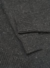 A detailed close-up shot of the Black Wool Fleck Roll Neck, showcasing the fine ribbed collar detail, premium recycled wool fabric, and the distinctive speckled fleck pattern throughout the garment.
