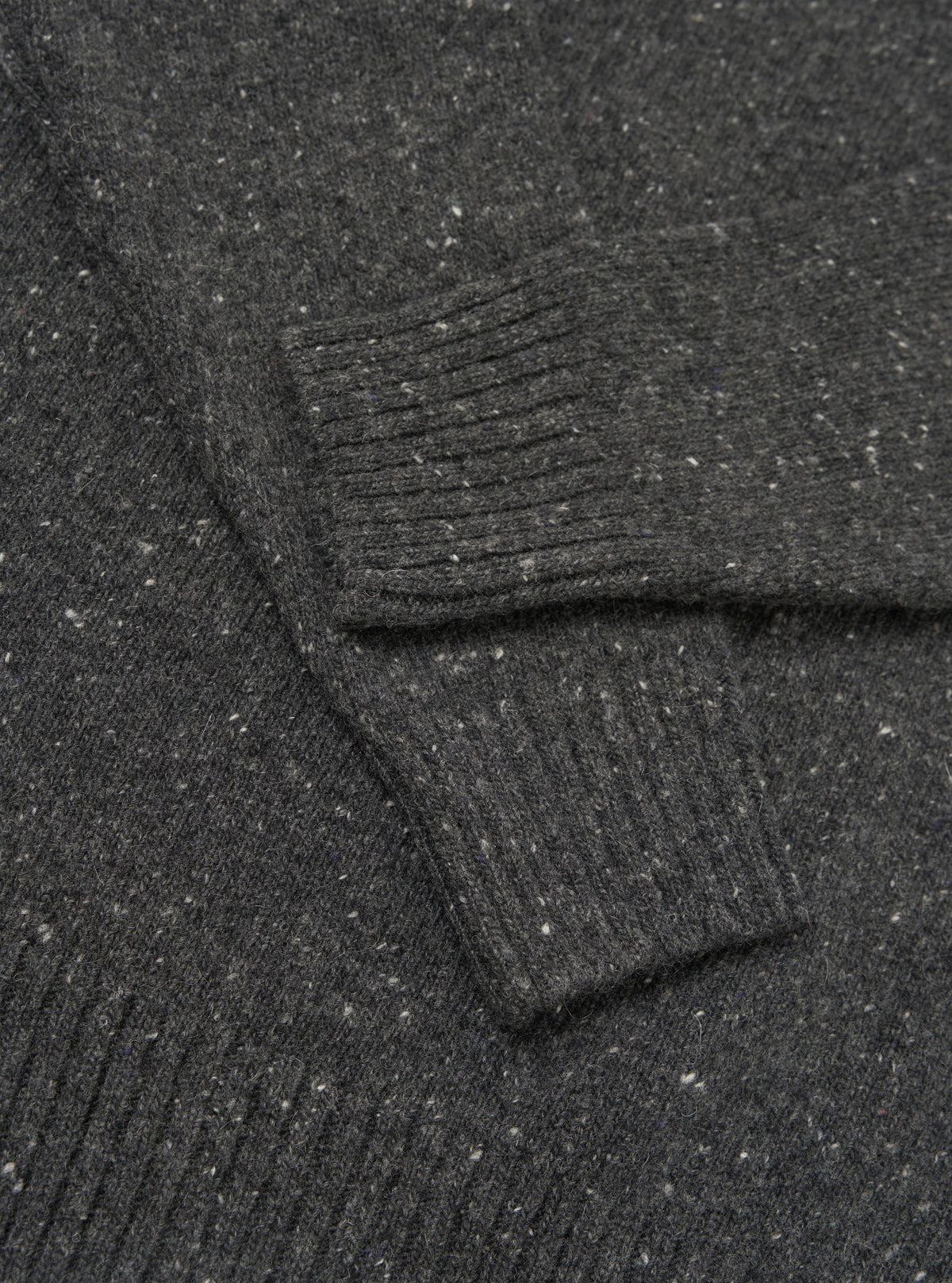 A detailed close-up shot of the Black Wool Fleck Roll Neck, showcasing the fine ribbed collar detail, premium recycled wool fabric, and the distinctive speckled fleck pattern throughout the garment.