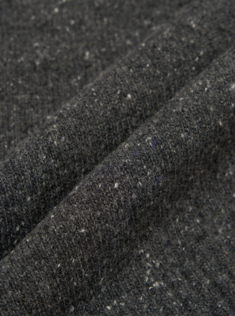 A close-up fabric swatch view of the Black Wool Fleck Roll Neck on a light backdrop, emphasizing the rich black recycled wool material integrated with subtle flecked texture details throughout.