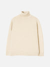 A model wearing the Fawn Wool Fleck Roll Neck against a plain studio background. The jumper showcases a high roll neck collar, long sleeves, ribbed hem, and a subtle flecked recycled wool pattern.